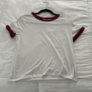 Medium, white, red trimmed t shirt with short sleeves.
